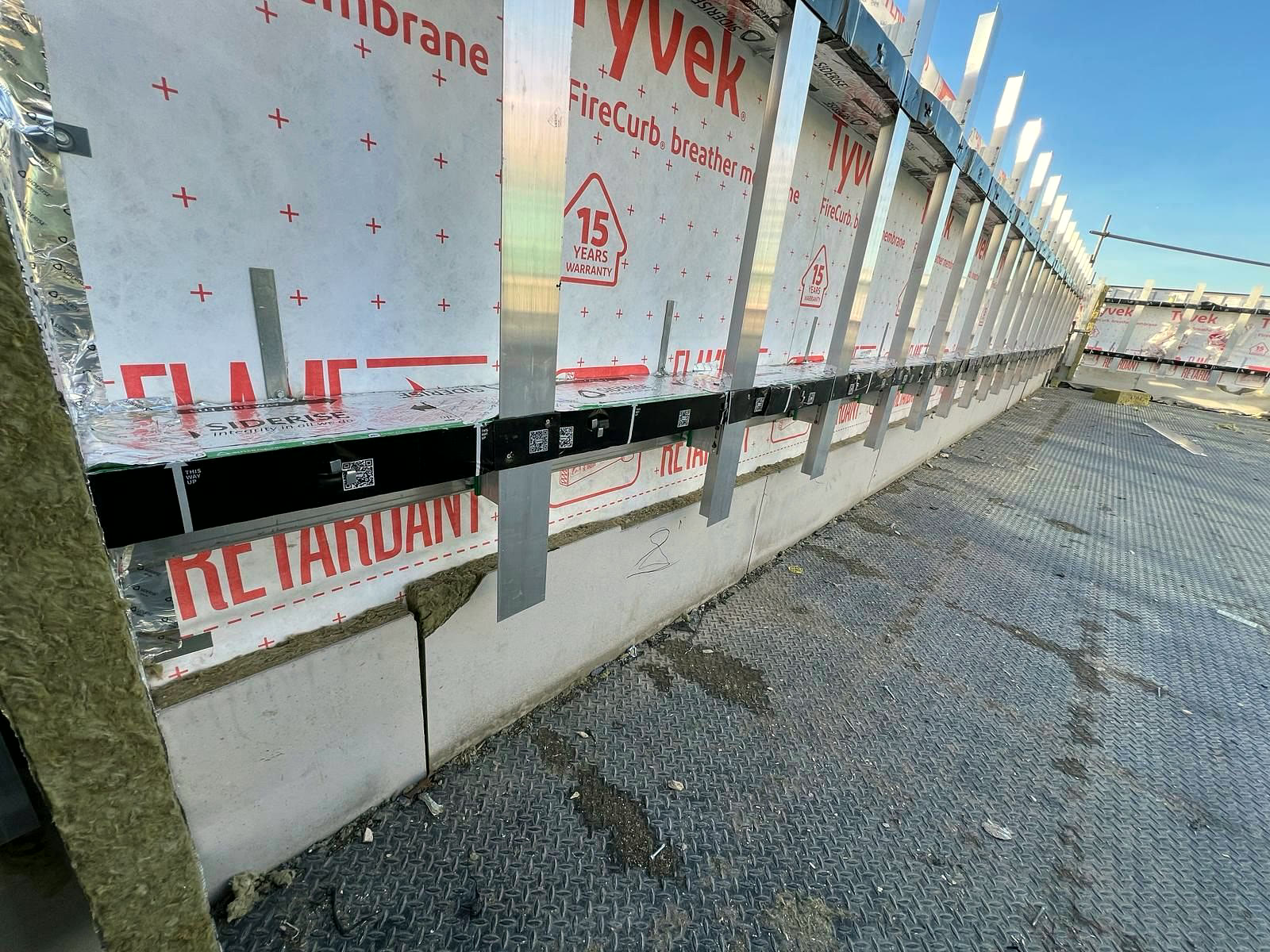 Cavity barriers and cladding rails over fire-retardant breather membrane at roof level