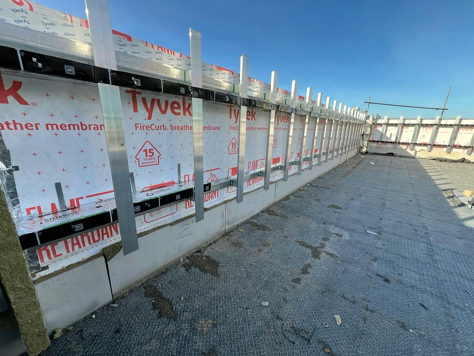 Long run of cladding rails and cavity barriers along a roof-level facade