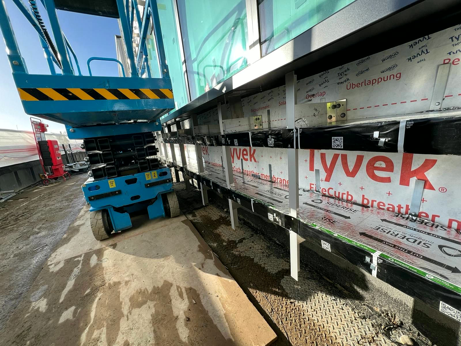Ground-floor facade cavity barriers installed from a scissor lift